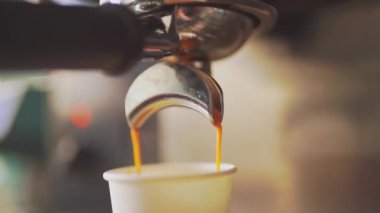 4K, espresso kahve makinesinden beyaz kağıt bardağa dökülüyor, yavaş çekimde.