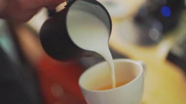 4k, kahve barmeni kapuçino, latte sanatı, yavaş çekim için espresso kahvesine süt koyuyor.