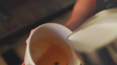 4k, kahve barmeni kapuçino, latte sanatı, yavaş çekim için espresso kahvesine süt koyuyor.