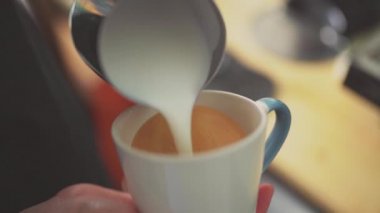 4k, kahve barmeni kapuçino, latte sanatı, yavaş çekim için espresso kahvesine süt koyuyor.