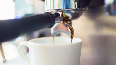 Kahve makinesinden beyaz fincana espresso dökülüyor.