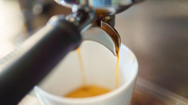 Kahve makinesinden beyaz fincana espresso dökülüyor.