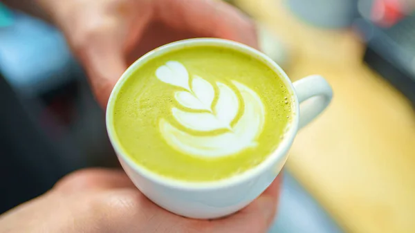 Barista segurando uma xícara de latte matcha em suas mãos — Fotografia de Stock