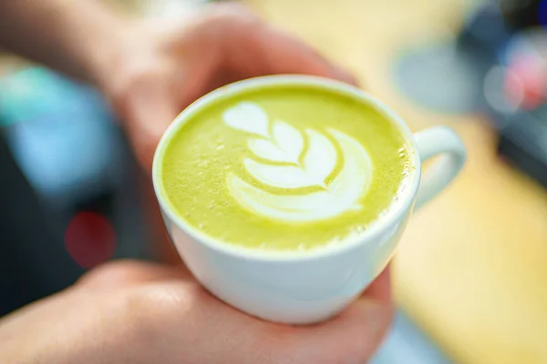 Barista segurando uma xícara de latte matcha em suas mãos — Fotografia de Stock