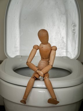 Tuvalette oturup karnını tutan bir insan figürü, kabızlık, karın ağrısı, zehirlenme ve ishal, viral enfeksiyonlar ve bakteri kavramı.
