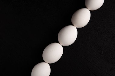 Siyah arka planda beyaz tavuk yumurtaları. Çiftlik ürünleri. Doğal yumurtalar. Tavuk yumurtaları masada.