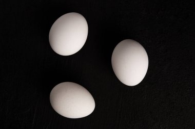 Siyah arka planda beyaz tavuk yumurtaları. Çiftlik ürünleri. Doğal yumurtalar. Tavuk yumurtaları masada.