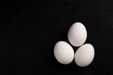 Siyah arka planda beyaz tavuk yumurtaları. Çiftlik ürünleri. Doğal yumurtalar. Tavuk yumurtaları masada.