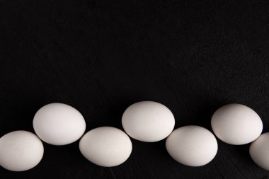 Siyah arka planda beyaz tavuk yumurtaları. Çiftlik ürünleri. Doğal yumurtalar. Tavuk yumurtaları masada.