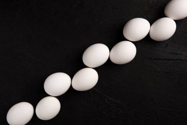 Siyah arka planda beyaz tavuk yumurtaları. Çiftlik ürünleri. Doğal yumurtalar. Tavuk yumurtaları masada.