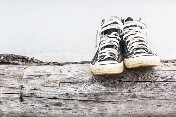 Zapatillas negras en las viejas paredes de madera de tronco y hormigón gris — Foto de Stock