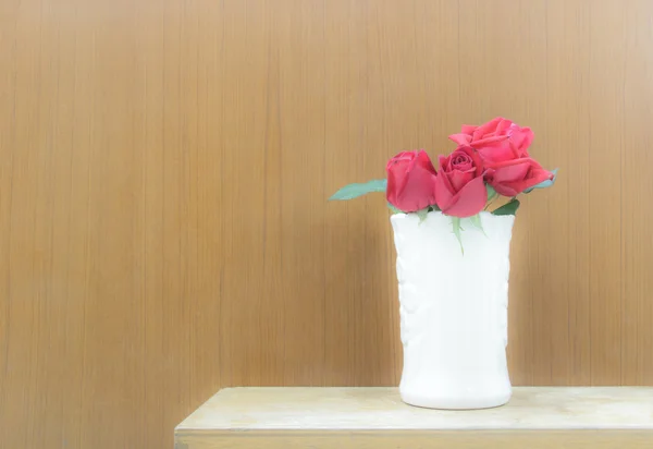 Roses rouges Dans un vase blanc sur une caisse en bois. Mur en bois backgro — Photo