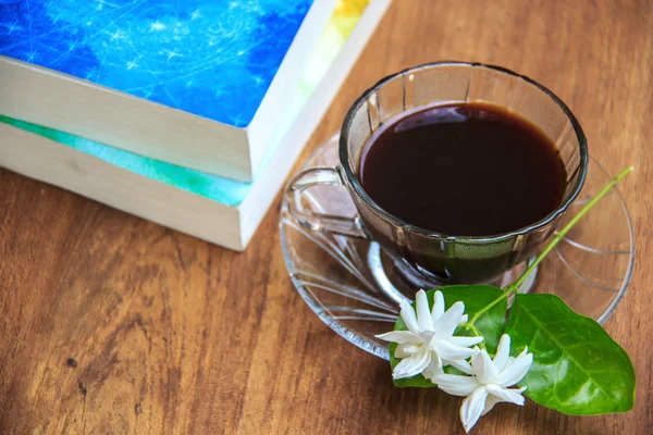 Café noir sur table en bois avec de vieux livres et fleur de jasmin — Photo