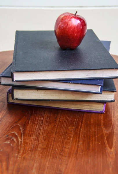 Red apple and old books on wooden tabletop — Stock Photo, Image