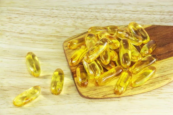 Fish oil capsules on wooden spoon — Stock Photo, Image
