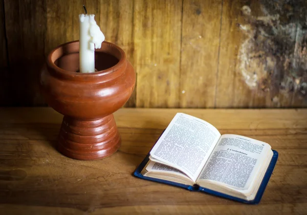 Bible a bílé svíčky na dřevěný stůl — Stock fotografie