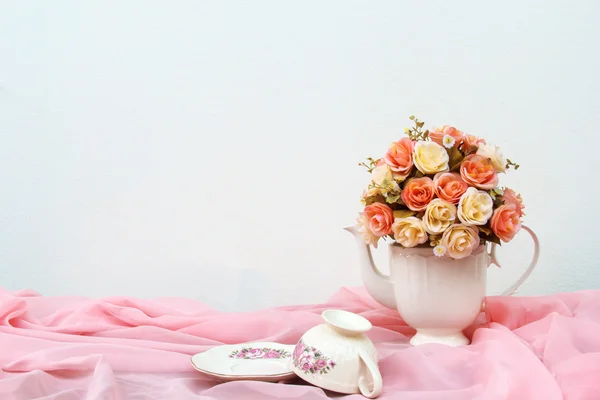 Bouquet of roses in white jug on wooden table and gray concrete walls — Stock Photo, Image