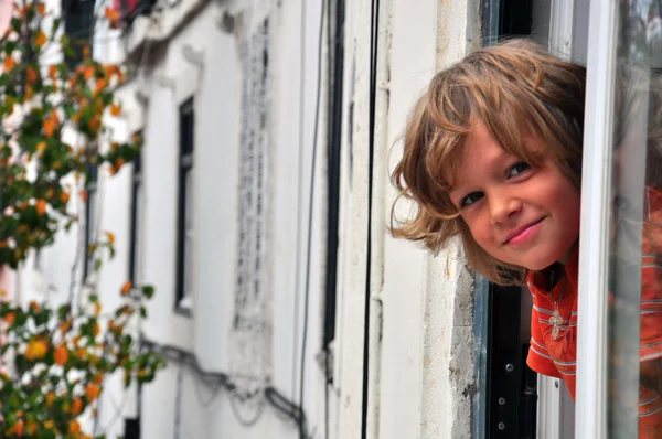 Smiling little boy in the window — Stock Photo, Image