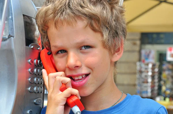 Lachende jongen praten door openbare telefoon — Stockfoto