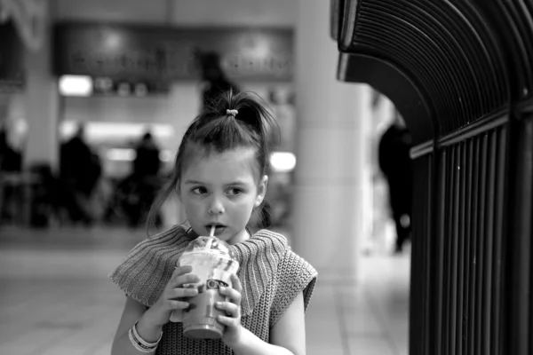 Monokrom bild av lilla flickan dricker milkshake genom sugrör — Stockfoto