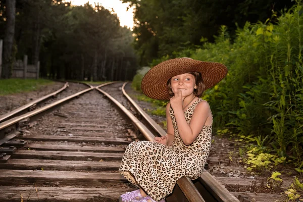 Tren rayların üzerinde oturan küçük kız — Stok fotoğraf