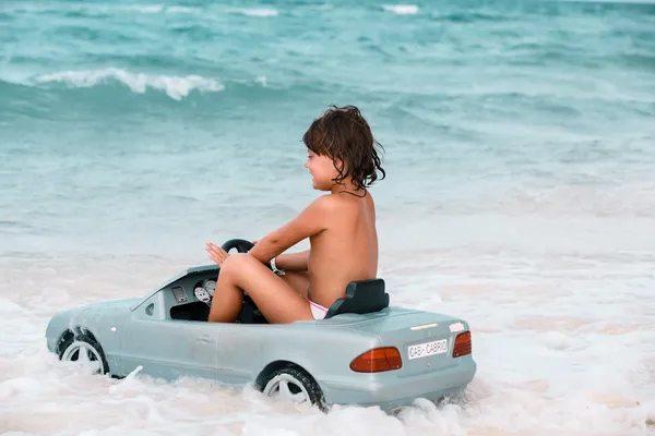 Ragazzina che guida una macchina verso l'oceano — Foto Stock