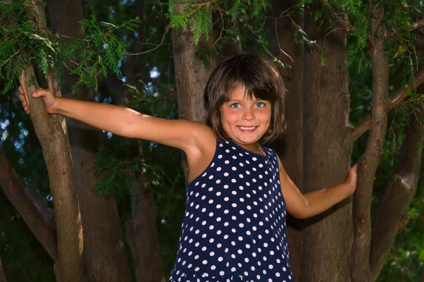 Smiling and happy little girl standing in dark woods — Stock Photo, Image