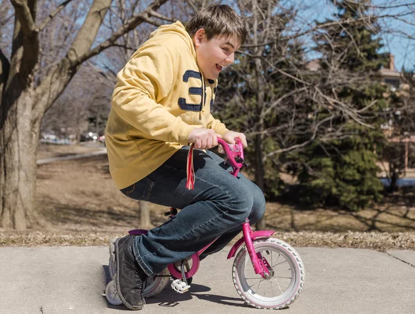 Big funny teenage boy riding small bike — Stock Photo, Image