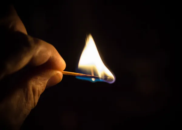 Brinnande tändsticka mot svart bakgrund — Stockfoto