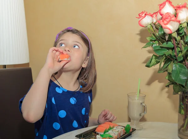 Hungriga vacker liten flicka tittar upp och äta sushi — Stockfoto