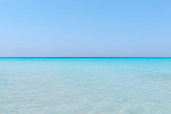 Бирюзовый спокойный океан сливается с чистым красивым небом на горизонте линии в солнечный теплый день — стоковое фото