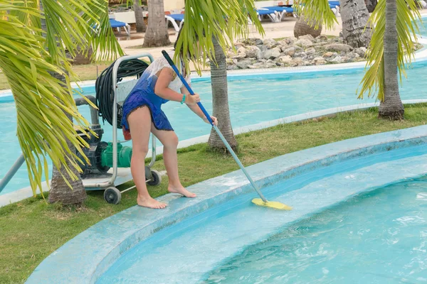 Girl cleaning the swimming pool border with broom — Stock Photo, Image