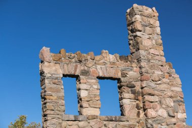 Terk edilmiş, tamamlanmamış, mavi gökyüzü arkaplanındaki taş duvar yapısı hakkında detaylı bir bakış açısı, kavramsal