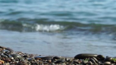 Çakıl taşları plajına yakın çekim. Dalgalar pürüzsüz çakıl taşlarına çarpıyor ve kıyıları yalıyor. Meditasyon için donanma geçmişi. Kopya alanı ile farklı tasarım amaçları için yaz arkaplanı modayı