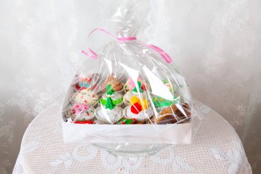 İçinde ev yapımı kekler, çörekler ve Noel tarzında süslemeler olan bir hediye kutusu. Geleneksel dekoratif sembollerle süslenmiş Noel mini tatlı kekleri.