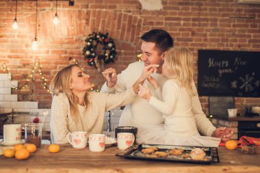 Mutlu aile - Anne, baba ve kız çatı katı tarzı mutfakta Noel kurabiyeleri pişirip oynuyorlar.