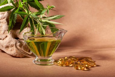 Et suyu kayığı ya da sürahi ve kenevir yağlı kapsüller, doğal taşın üzerine kenevir yaprağı dalları kağıt üzerinde, kopyalama alanı olan..