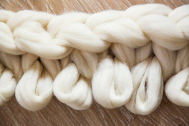 Merino yününden büyük bir ekose örme işlemi. Ahşap zeminde açık döngülerle tamamlanmamış iş