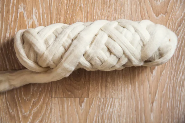 木地板上的一串大针织米黄色长毛线 — 图库照片