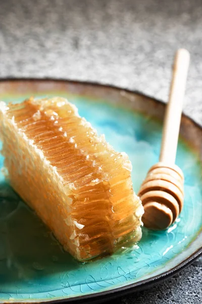 Amidon de miel scellé avec trempette à miel en bois pour mélanger et déguster du miel naturel sur une assiette en porcelaine bleue sur une table blanche — Photo
