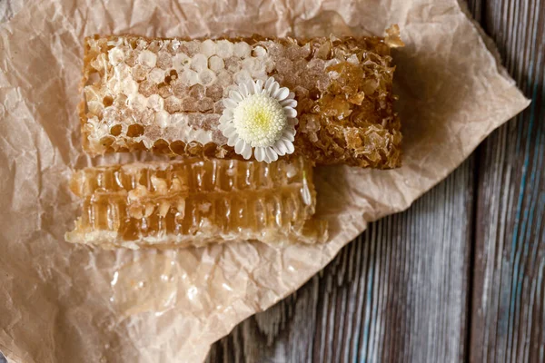 Peigne en nid d'abeille scellée de miel sur papier parchemin sur table en bois — Photo
