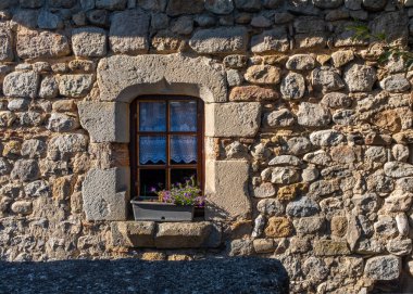 A small window on an historical house in the Southern France town of Joyeuse, Ardeche, taken on a sunny summer morning with no people