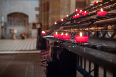 Several red candles with blurred background in St. Peter and St. Paul abbey located in Wissembourg, France, with no people