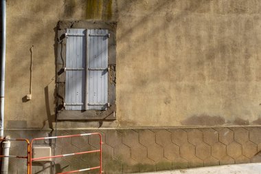 A typical window with grey shutters of the Southern France village of Tournissan, with no people, taken on a sunny end of winter day