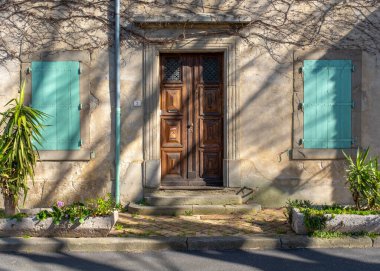 A typical derelict building facade with closed shutters in a Southern France village, with no people, taken on a sunny end of winter day
