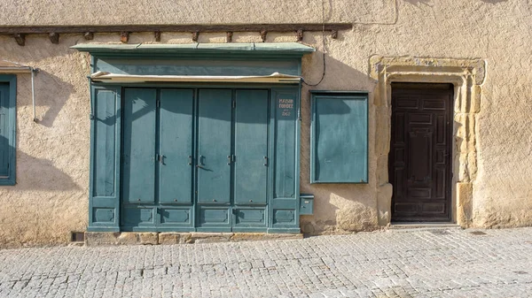 A closed shop set in a stone building with blue shutters in a Southern France village