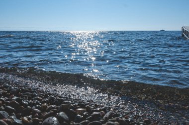 Baykal Gölü kıyısı. Su, güneşte parlayan taşları temizler.