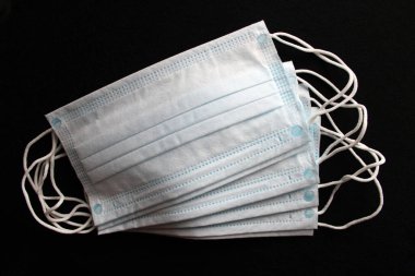 Tıbbi maskeler. Siyah arka planda tek kullanımlık tıbbi maskeler. Açık mavi.
