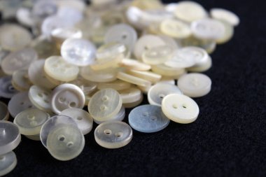 Küçük beyaz düğmeler. İki delikli plastik düğmeler. Gömlek için düğme. Siyah arkaplanda beyaz ayarlar. 