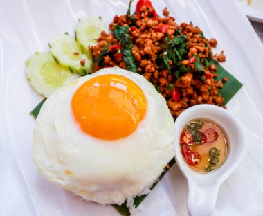 Yakın plan pirinçli, kızarmış domuz eti, fesleğen ve sahanda yumurta.